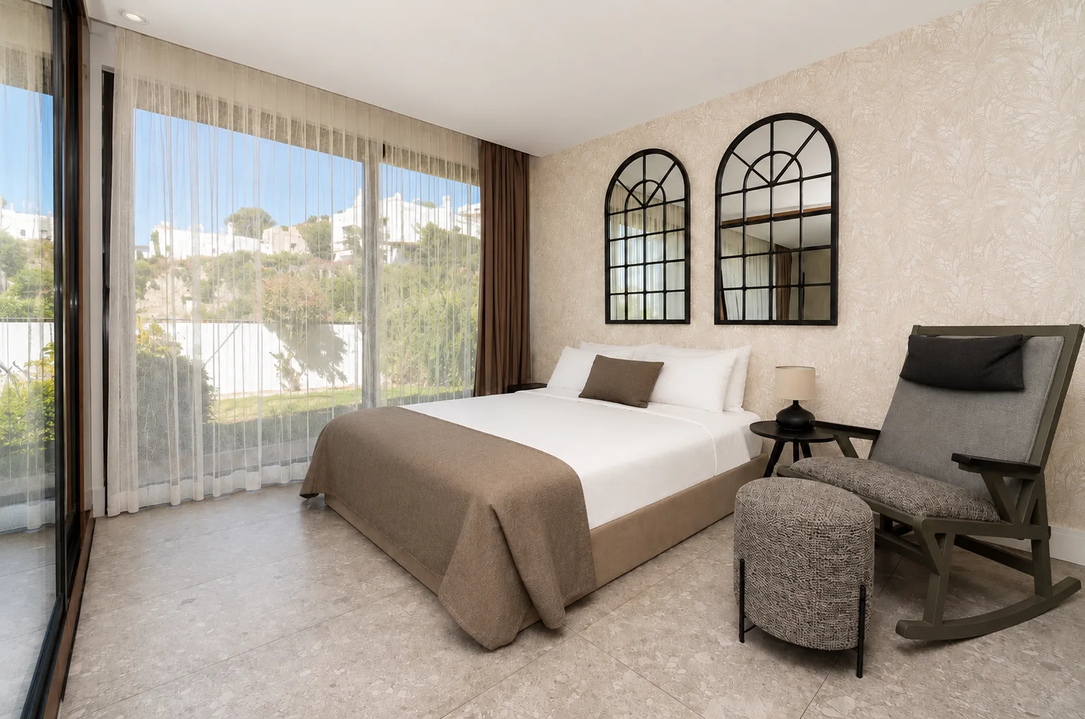 Garden View room with two arched mirrors, a rocking chair and full-height glass doors onto the garden