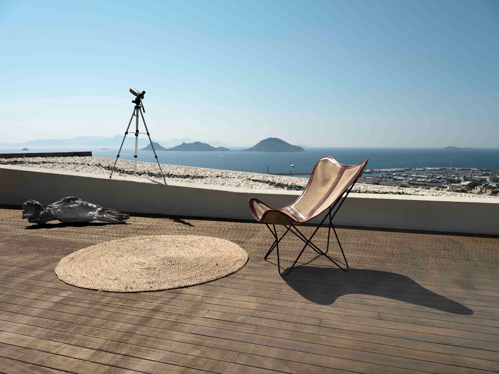 Warm minimal villa living room with linen sofas, stone floors and open doors to a terrace